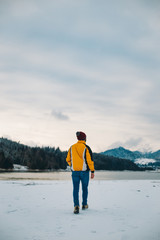 Young tourist man admire the amazing view of lake and mountain in the middle of winter with snowy forest , he is the elated of the landscape