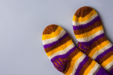 Handmade warm knitted woolen multicolored striped socks on gray background. Winter autumn eco...