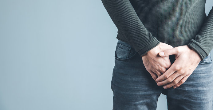 Man Holding His Urethra In Pain On Gray Background