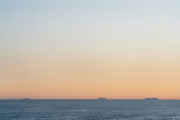 Naklejka na ściany i meble Sea view at sunset with 3 vessels far away , minimalistic look