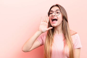 young pretty woman yelling loudly and angrily to copy space on the side, with hand next to mouth...