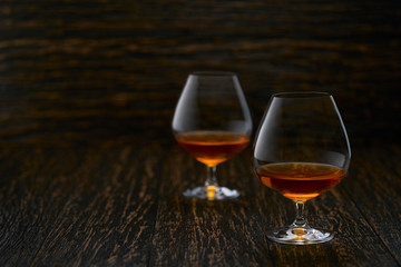 Two glasses of brandy or cognac  on a wooden table with copy space.