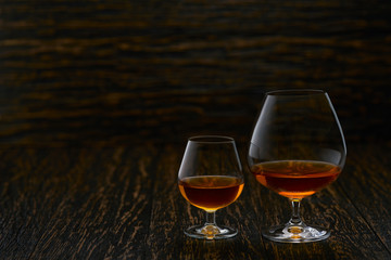 Two glasses of brandy or cognac  on a wooden table with copy space.
