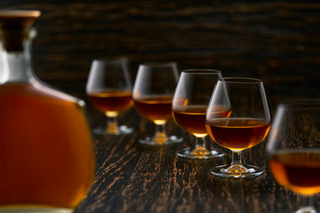 glasses of cognac on a wooden table with the silhouette of a bottle of cognac.