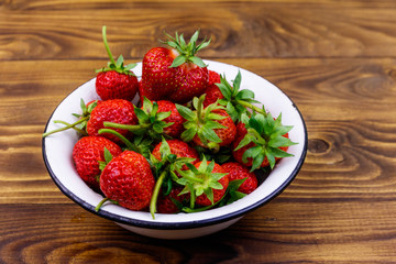 Fresh ripe strawberry in white bowl on a wooden table