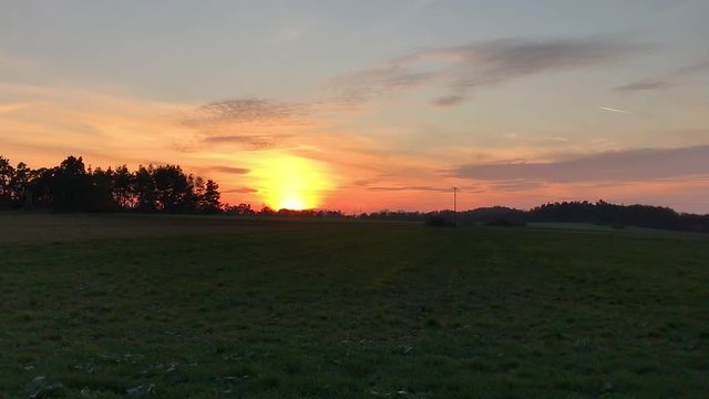 Sunset with sun in colorful sky over hill on fields (Full HD)