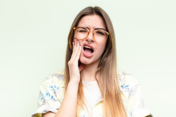 young pretty woman holding cheek and suffering painful toothache, feeling ill, miserable and...