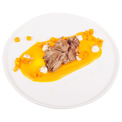 Meat with pumpkin mousse on white plate isolated.