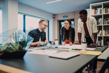Laughing young colleagues working on project