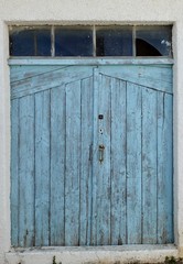 old blue window shutters with broken glass above