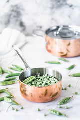 Green baby peas in pan on white background. copy space