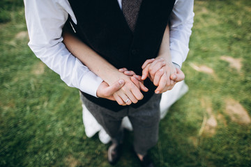 The groom holds the groom's hands. Wedding rings on fingers