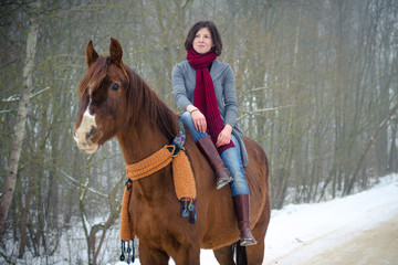 portrait of girl riding red trakehner stallion horse with scarf in winter