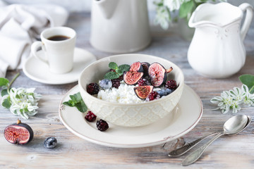 Cottage cheese with figs, berries, honey. Cup of coffee and coffee pot. Breakfast. Wooden table.