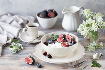 Cottage cheese with figs, berries, honey. Cup of coffee and coffee pot. Breakfast. Wooden table.