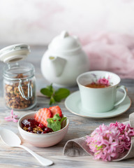 Spring Breakfast with granola and fresh strawberries and lychee and flowers on wooden background.