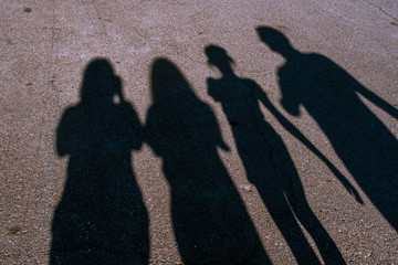 Shadows of four people on the pavement