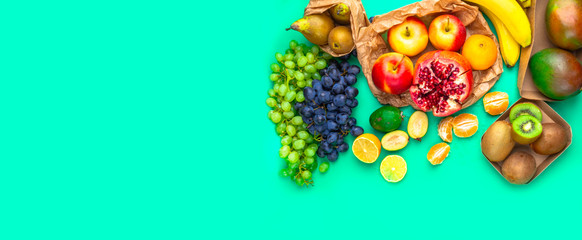 Naklejka premium Fruits rich in antioxidants, vitamin and fiber on trendy mint green background. Flat lay. Raw, vegan, vegetarian, alkaline food concept.