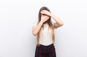 young pretty woman covering face with both hands saying no to the camera! refusing pictures or...