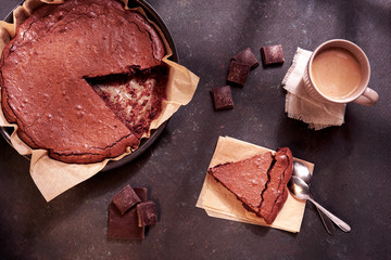Dark chocolate dessert - homemade brownie cake with pieces of dark chocolate, cup of coffee, spoons...