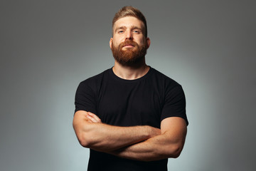 Fabulous at any age. Portrait of charismatic muscular 30-year-old man standing over dark gray background. Perfect haircut. Rocker, biker, hipster style. Copy-space. Studio shot