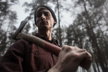 Strong lumberjack with the ax in the forest.Stylish lumberman getting ready for work. Lifestyle.