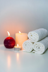 Fototapeta na wymiar SPA and wellness photo with stack of white towels and candles light, vertical orientation.