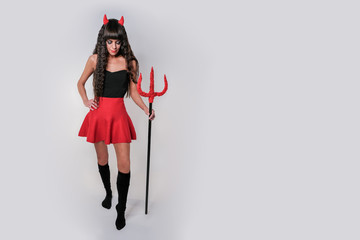 An isolated demon looks down with a trident in his hands. Demon girl with a trident in her hands and horns.