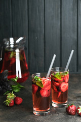 Homemade fresh strawberry lemonade with basil leaves on a dark background copy space.