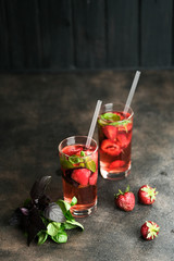 Homemade fresh strawberry lemonade with basil leaves on a dark background copy space.