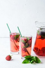 Homemade fresh strawberry lemonade with basil leaves on a light background copy space.
