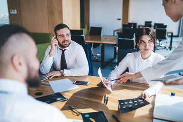 Fototapeta premium Smart woman pointing with pan to document in hands of colleague