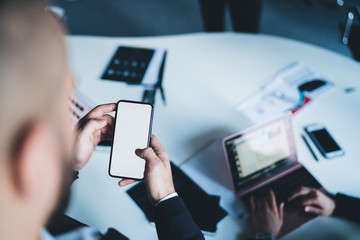 Crop businessman browsing smartphone in office