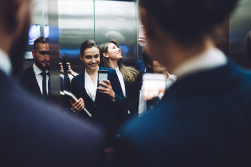 Cheerful coworkers taking selfie while standing in elevator together