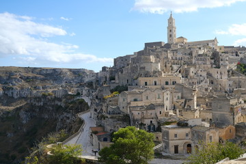 Fototapeta na wymiar View of the city of Matera in Italy. Church with bell tower and houses built in beige tuff stone.