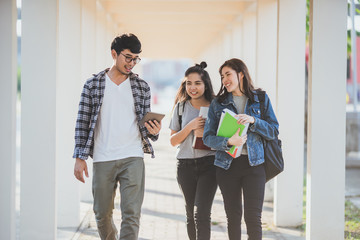 Asian young student are walking and talking with friends in university hall during break and communicating.