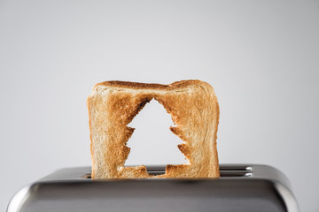 Hole in a form of christmas tree on roasted toast bread popping up of stainless steel retro toaster...