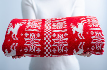 Woman holding folded red Christmas plaid on gray light background, space for text