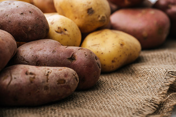 organic raw potatoes on brown rustic sackcloth