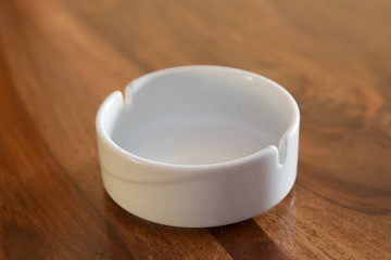 Close up, selective focus, shallow depth of view. Round glass ashtray isolated on wooden background . Clean empty round glass ashtray on an old wooden table in a park.