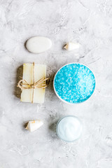 Fototapeta na wymiar blue salt, body cream and shells for spa bath background top view mockup