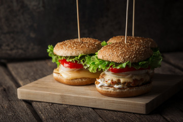 Fresh tasty grilled beef burgers with cheese wood background.