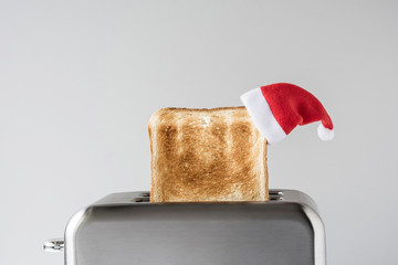 Roasted toast bread in a christmas Santa Claus red hat popping up of stainless steel retro toaster...