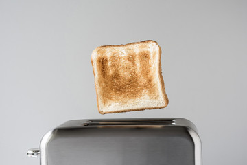 Roasted toast bread popping up of stainless steel retro toaster for breakfast preparation on a gray...