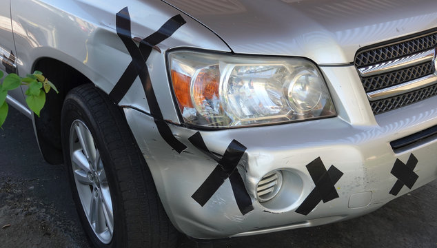 A car has its damage covered by whimsical bandages, taking the scratches with humor 