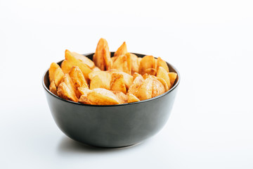 delicious golden potato wedges in bowl on white background