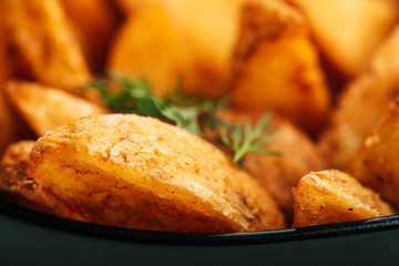 close up view of delicious golden potato wedges with dill in bowl