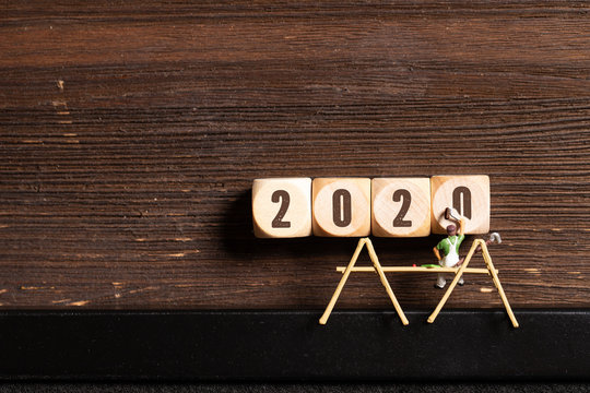 little painter figure and cubes with the number 2020 on wooden background