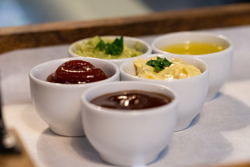 Small bowls with different sauces on a tray in a restaurant