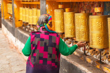 A pilgrim woman in traditional dress turns prayer mills and prays